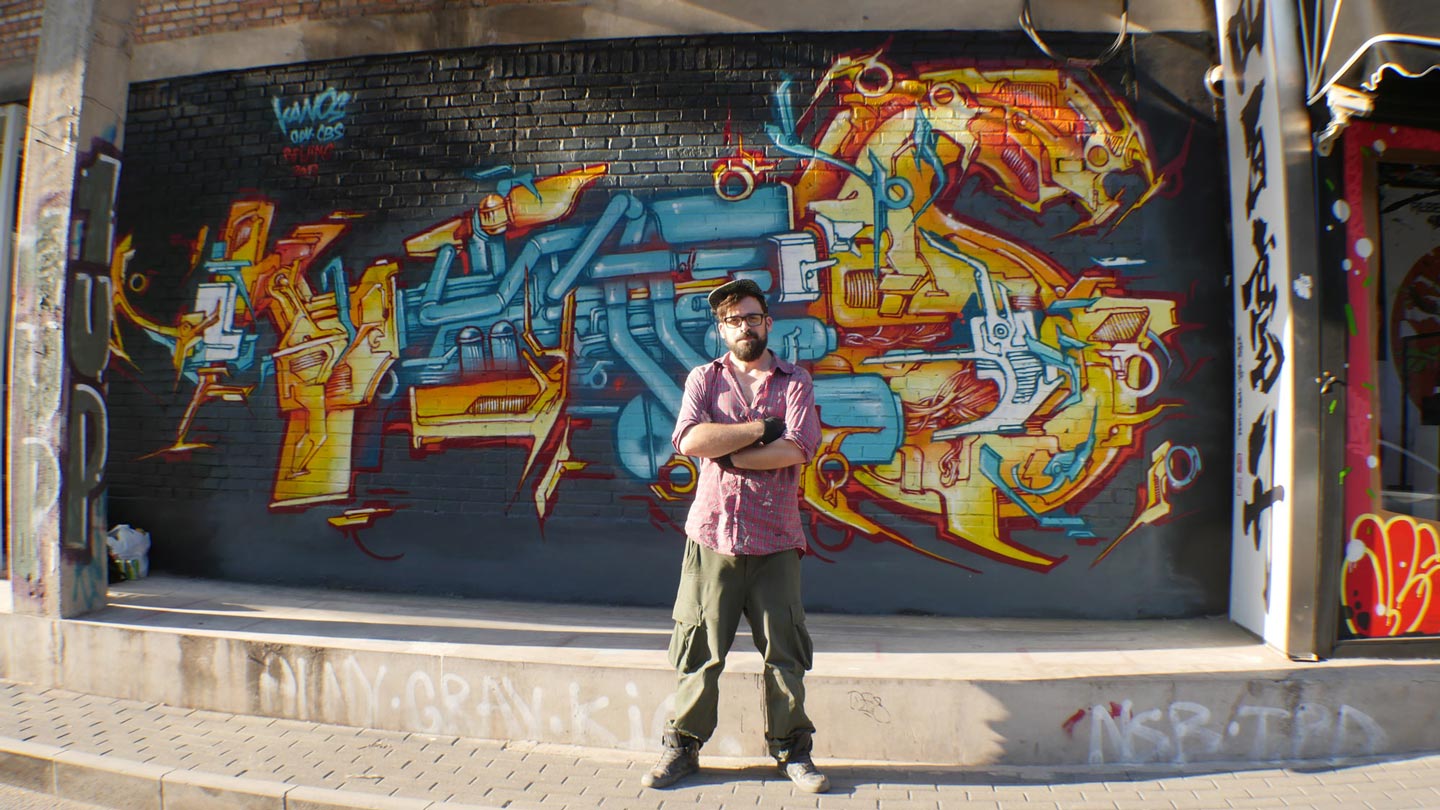 alex kanos is standing in front of a wall in beijing with yellow and turquoise