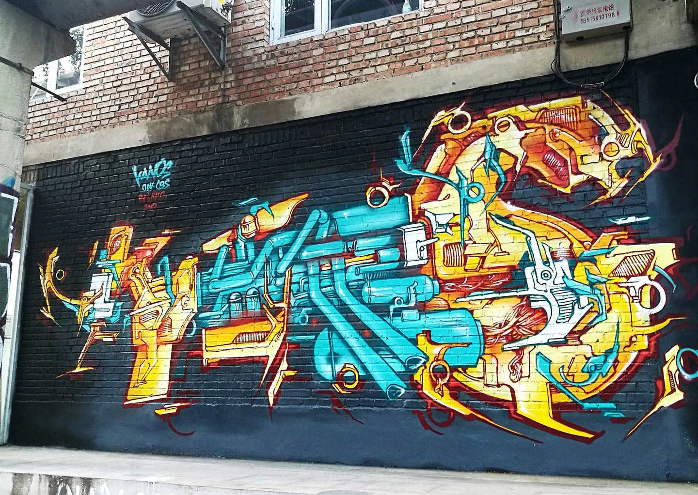 a graffiti of alex kanos on a wall in beijing with yellow and turquoise