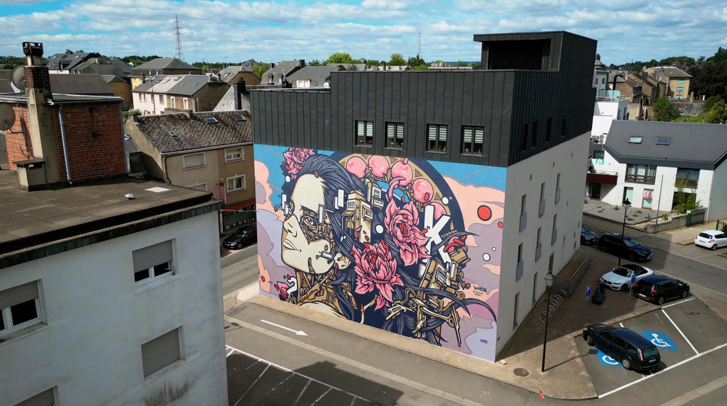 a street art mural made by alex kanos in aubange belgium representing a woman with mechanical parts and flowers, view by drone