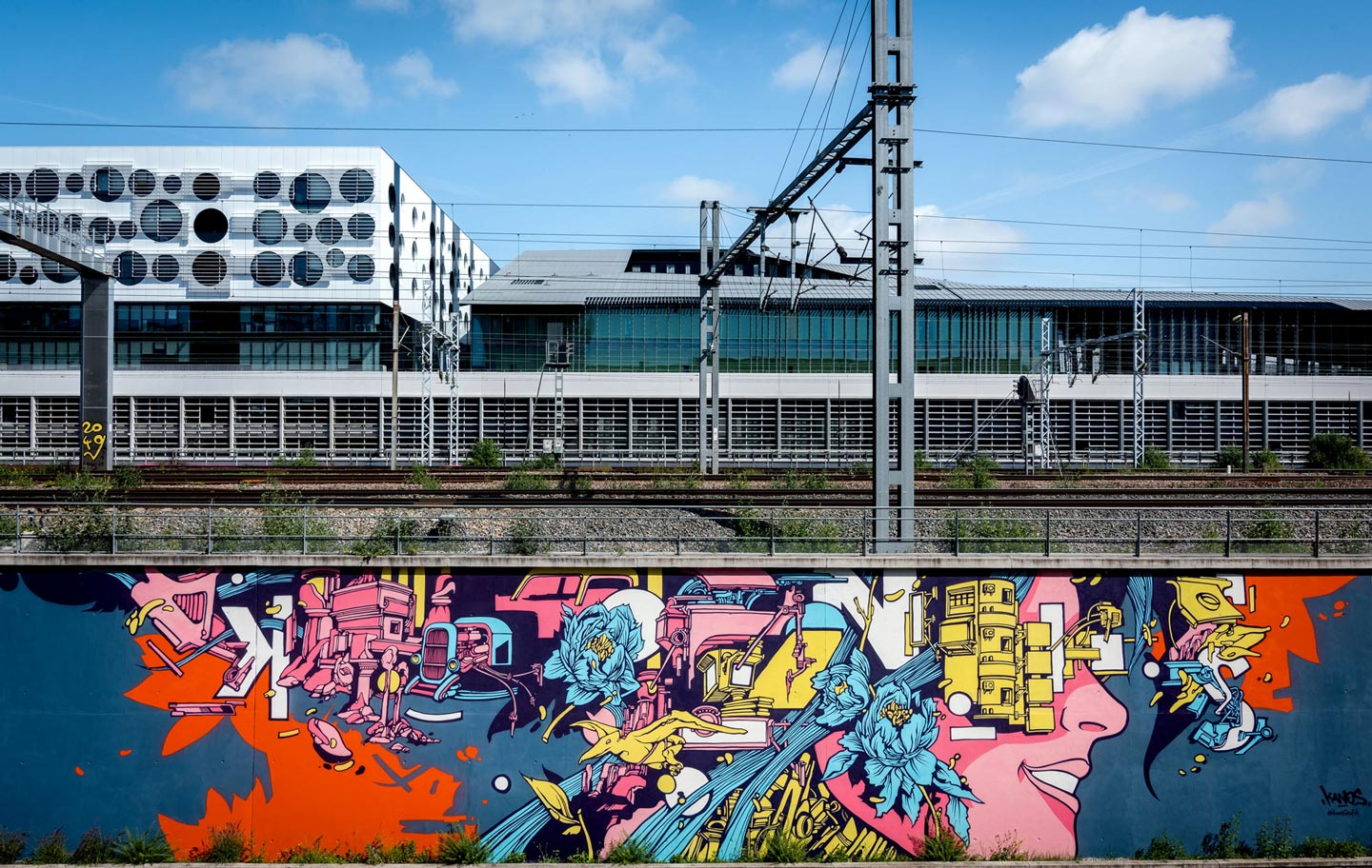 a street art mural made by alex kanos with railroad above